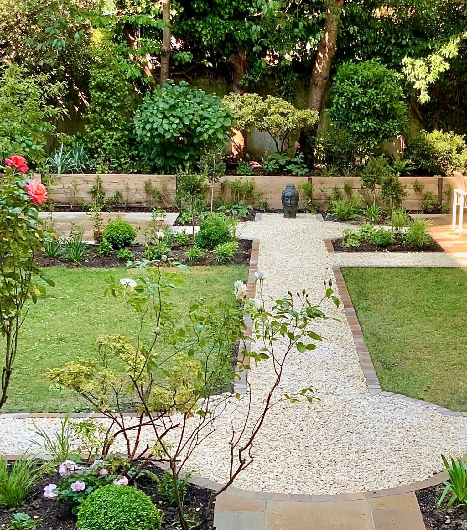 A considered garden showing sandstone paving, brick edging and mature planting