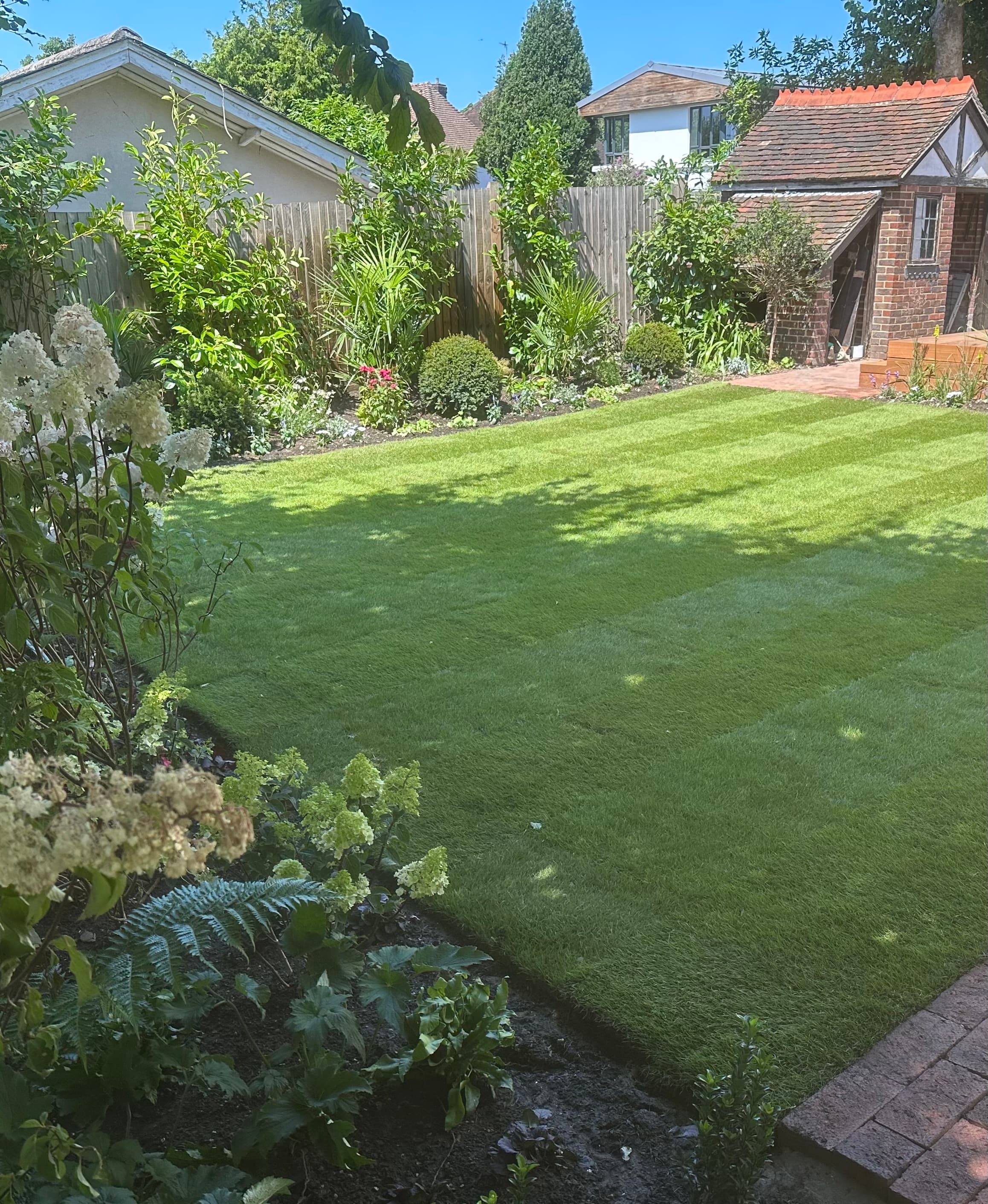 A finished garden with lawn, sandstone paving and raised deck